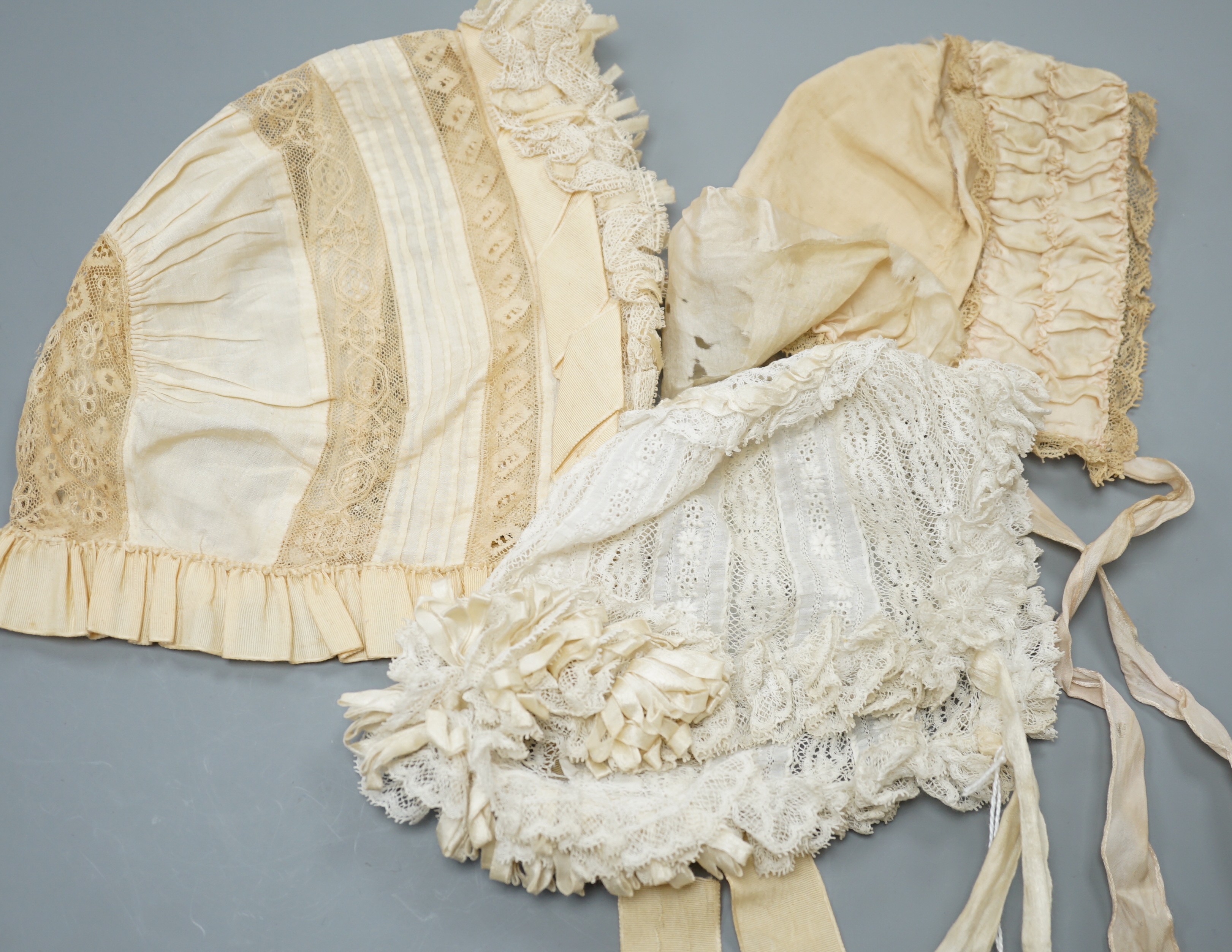 Three babies bonnets, two cream silk, one cotton